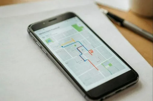 Smartphone affichant une carte de suivi, posé sur un contrat, drapeau belge en arrière-plan