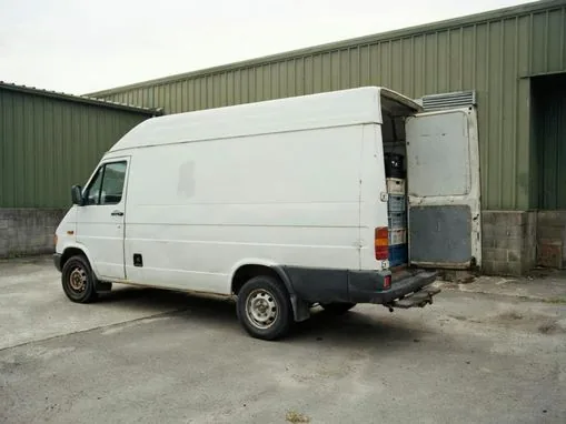 Camionnette utilitaire blanche sur un parking au crépuscule