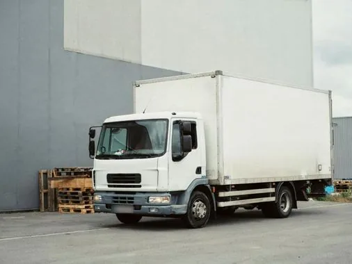 Camion porteur blanc sur un parking au crépuscule